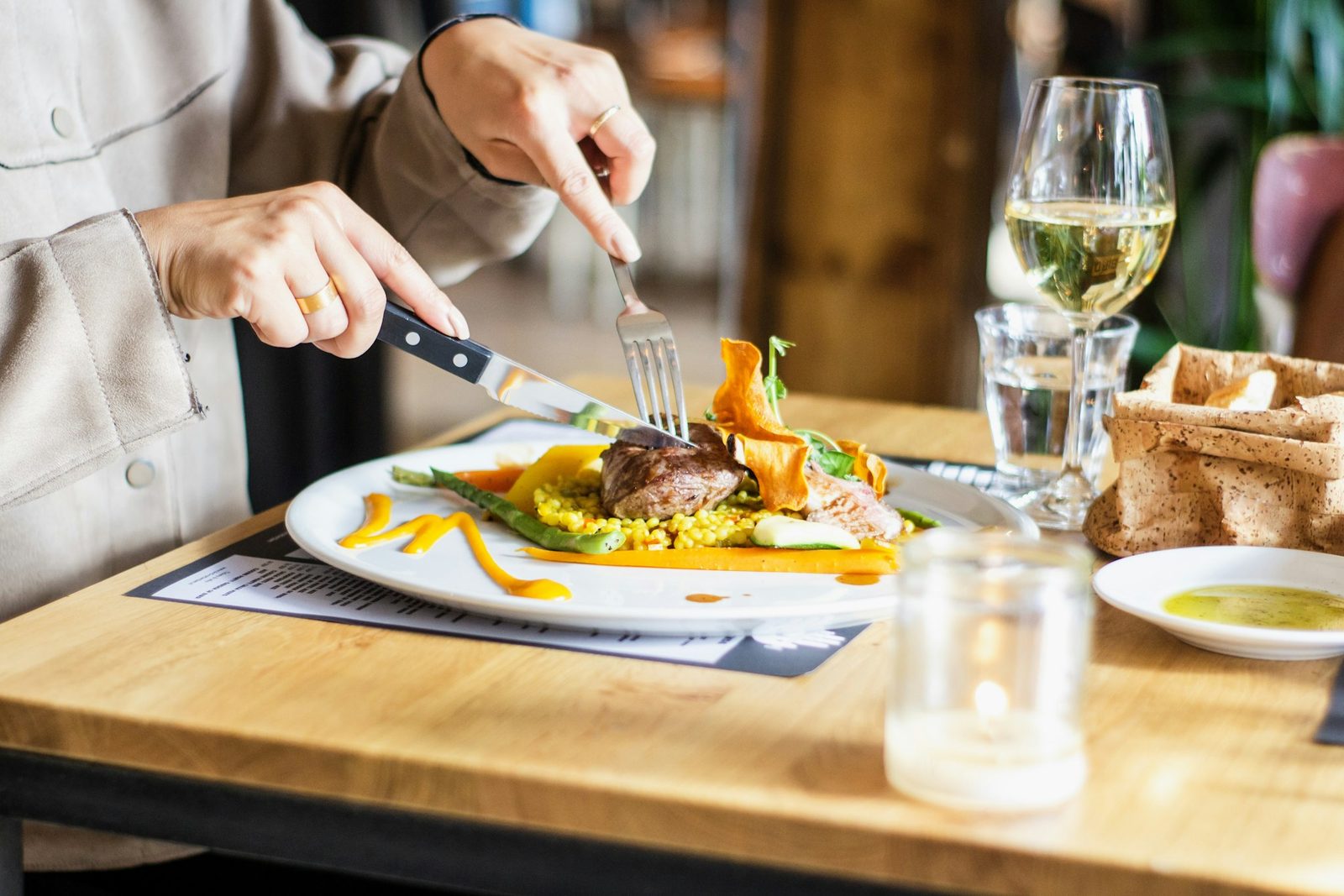 A plated meal being served at a restaurant table with a glass of wine